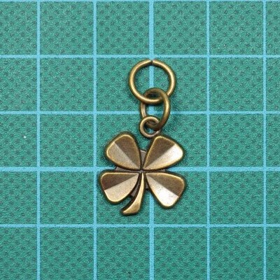 Pingente trevo de quatro folhas em metal bronze sobre fundo quadriculado verde e azul