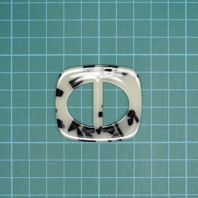 Fivela de plástico branco com manchas pretas sobre fundo de grade azul