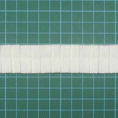 Fita elástica branca com textura nervurada sobre fundo quadriculado verde
