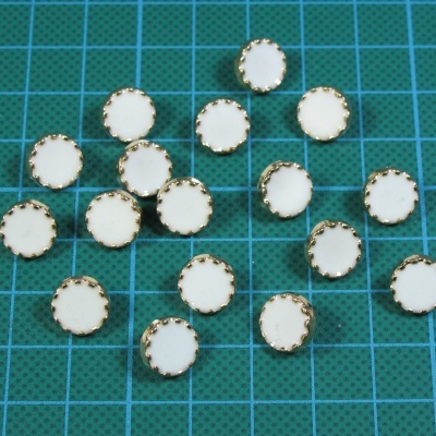 Peças circulares brancas com bordas douradas sobre superfície quadriculada verde