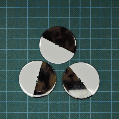 Três botões bicolores redondos sobre fundo quadriculado azul e verde