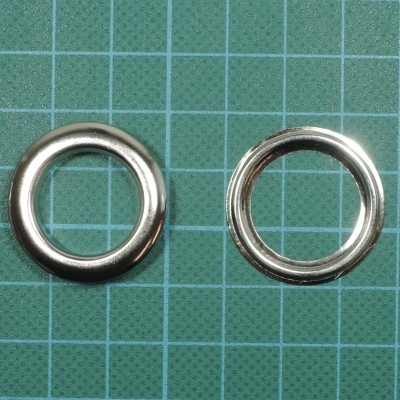 Dois anéis metálicos prateados sobre superfície verde quadriculada