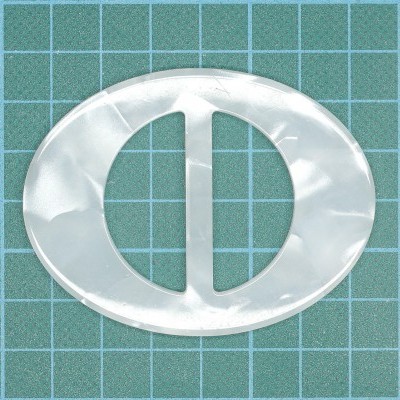 Peça oval transparente em plástico sobre base verde com grelha quadriculada