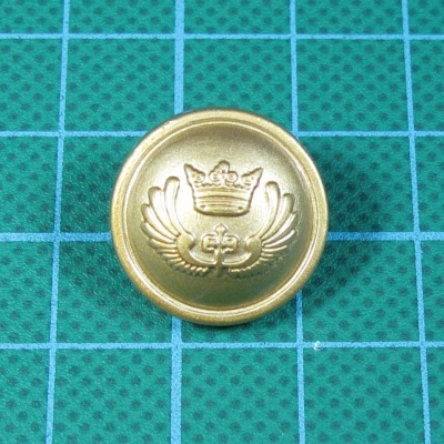 Botão dourado com coroa e asas sobre fundo verde quadriculado