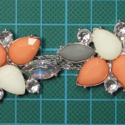 Brincos com pedras decorativas coloridas e cristais sobre fundo quadriculado verde