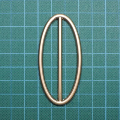 Fivela oval metálica dourada sobre superfície verde quadriculada