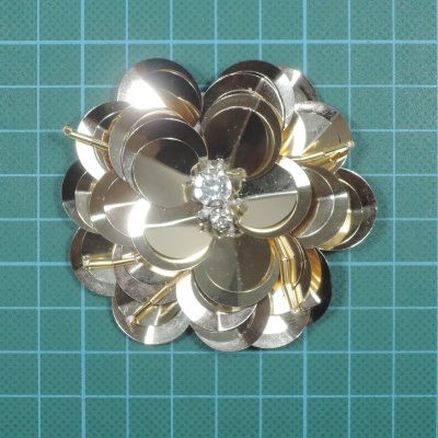Broche flor metálico dourado com pedras brilhantes no centro