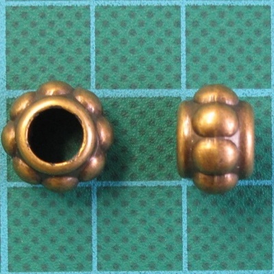 contas metálicas douradas com formato arredondado em superfície verde quadriculada