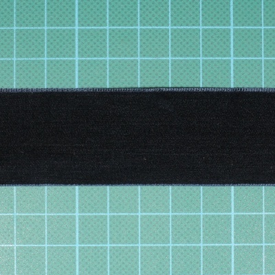 Faixa têxtil elástica preta sobre superfície verde com grelha branca