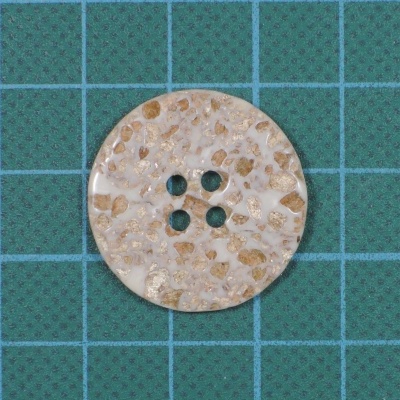 Botão redondo bege com quatro furos em folha verde quadriculada