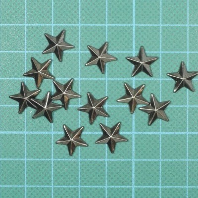 Tachas metálicas em forma de estrela sobre fundo verde quadriculado