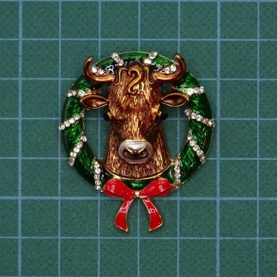 Broche cabeça de touro com coroa verde e laço vermelho