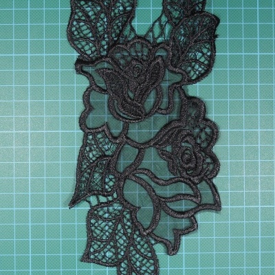 Aplicação em renda preta floral sobre fundo verde quadriculado