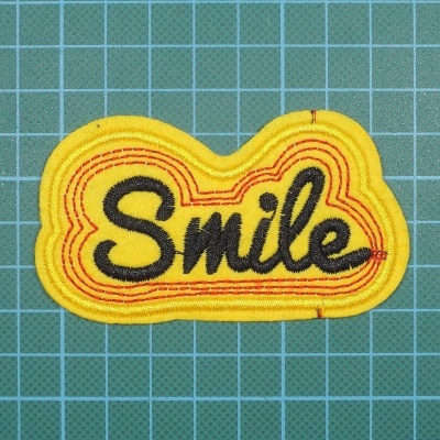Patch bordado amarelo com a palavra Smile em preto
