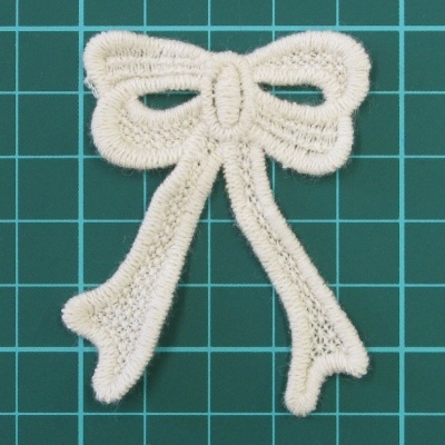 Laço branco bordado sobre superfície verde quadriculada