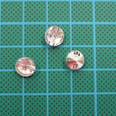 Três botões prateados sobre superfície verde quadriculada