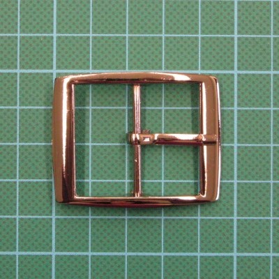 Fivela metálica dourada quadrada sobre fundo verde quadriculado