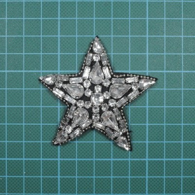 Broche em forma de estrela com pedras transparentes sobre fundo azul quadriculado