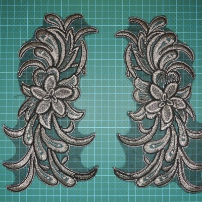 Bordados florais cinza e preto sobre superfície quadriculada verde