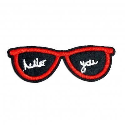 Aplique bordado em forma de óculos de sol com armação vermelha e lentes negras com texto branco