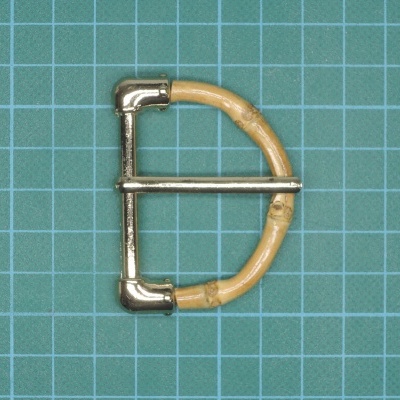 Fivela tipo D em metal prateado com revestimento em madeira clara sobre fundo verde de grade