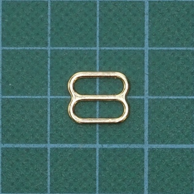 Anilha metálica dourada sobre tapete verde com quadrícula azul