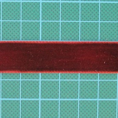 Fita de veludo vermelha com bordas douradas sobre superfície azul quadriculada