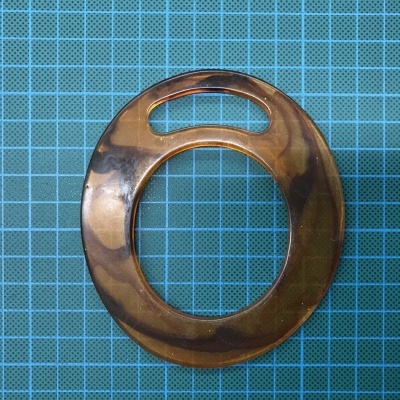 Prendedor redondo marmoreado castanho para lenço sobre superfície quadriculada azul