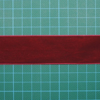 Fita vermelha de veludo com bordas douradas sobre superfície de corte verde