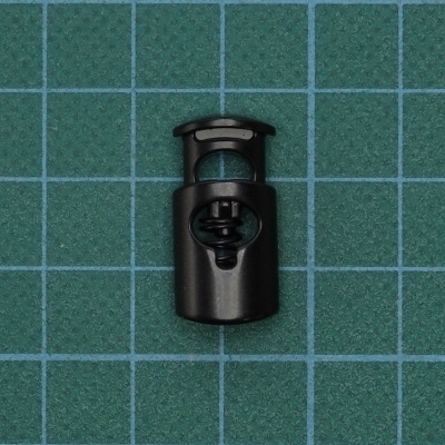 Acessório preto para cordão com mola em superfície verde com grelha azul