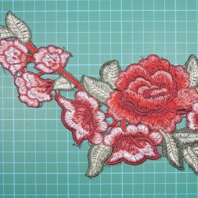 Aplicação bordada de flores vermelhas e rosas com folhas verdes em tecido