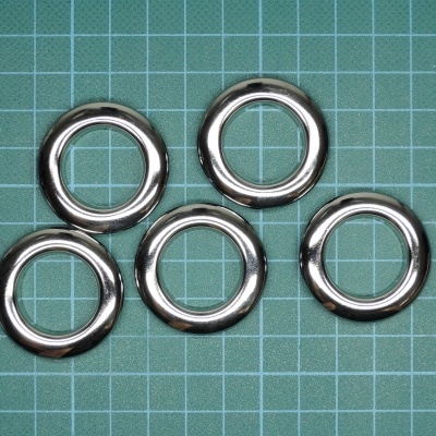 Cinco argolas metálicas prateadas sobre superfície verde quadriculada