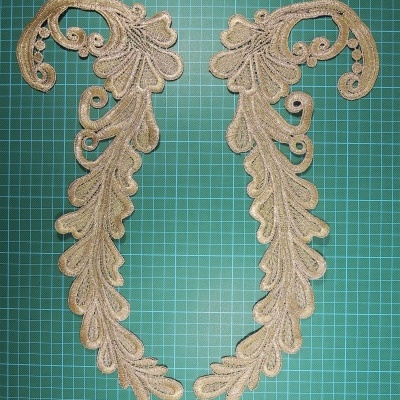 Par de apliques bordados bege com detalhes dourados sobre base verde quadriculada