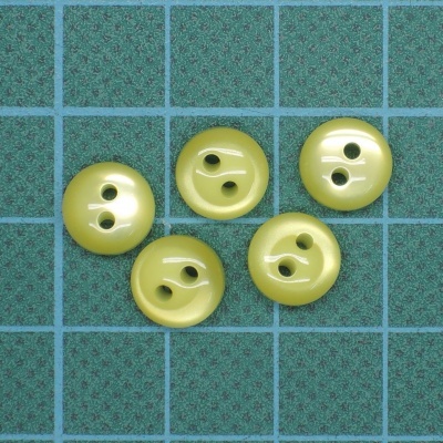 Cinco botões plásticos amarelos claros em superfície quadriculada azul