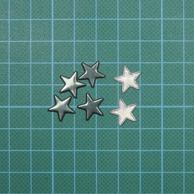 Seis estrelas metálicas prateadas e cinza sobre superfície quadriculada verde