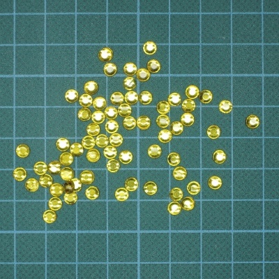 Pequenos botões ou tachas dourados sobre base verde com grade.