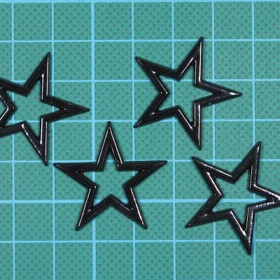 Moldes pretos em forma de estrela sobre superfície verde quadriculada