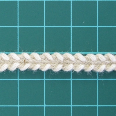 Cordão trançado de algodão cru e bege sobre superfície verde quadriculada