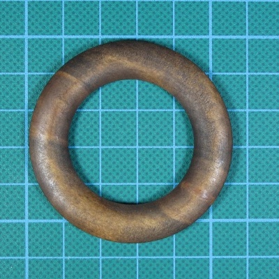 Anel de madeira castanho sobre base quadrícula azul.