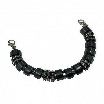 Pulseira preta com contas cilíndricas e anéis com strass sobre fundo branco