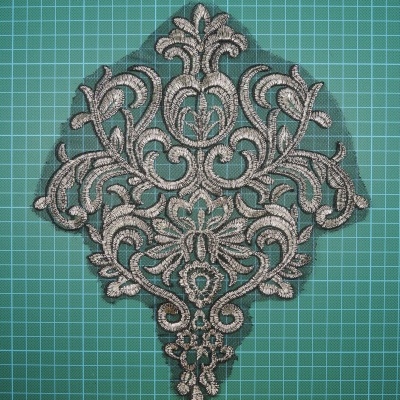 Aplicação de renda bege com padrão floral sobre superfície verde quadriculada