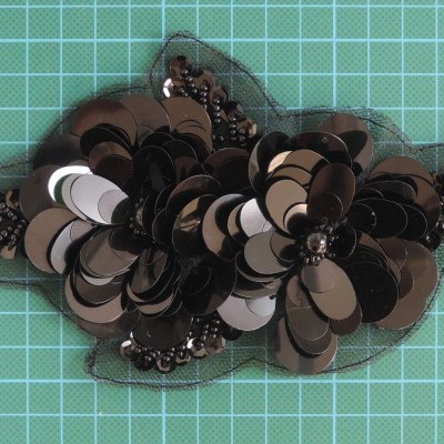 Aplicação decorativa de flores com paetês e miçangas em tecido transparente