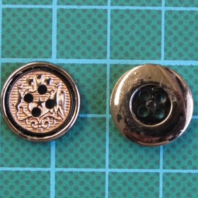 Dois botões metálicos redondos sobre base verde quadriculada