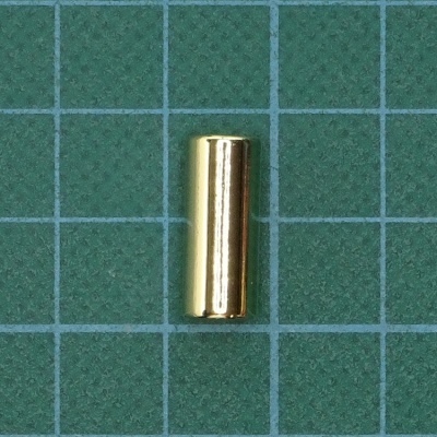 Objeto cilíndrico dourado sobre fundo verde quadriculado