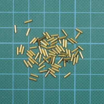 Pequenos tubos metálicos dourados sobre base quadriculada verde