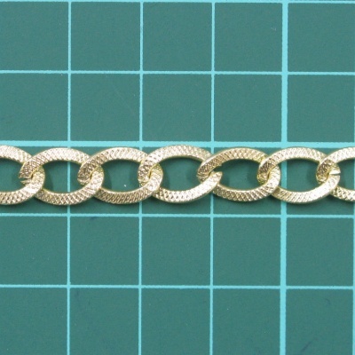 Corrente de elos dourados sobre superfície verde com grelha.