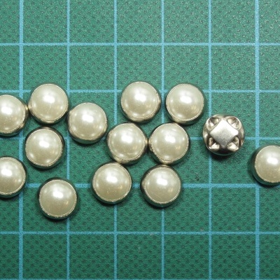 Botões pequenos redondos pérola e metálico sobre base verde quadriculada