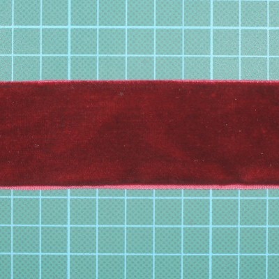 Tira de tecido vermelho veludo sobre fundo quadriculado verde