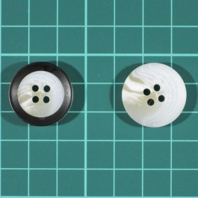Dois botões redondos de plástico com quatro furos, em superfície verde com grelha.