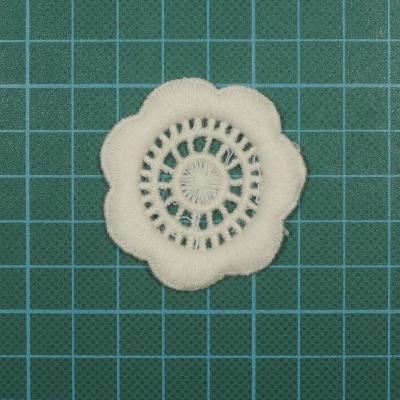 Flor decorativa branca em tecido sobre fundo verde em grade